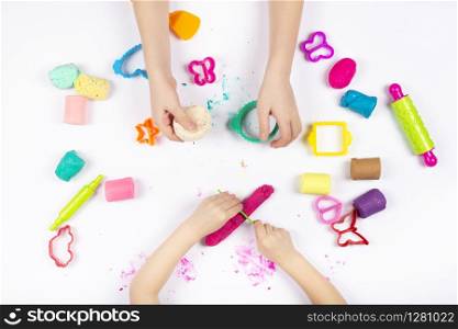 Little girls hands playing with colorful modeling clay on white background. Educational game with clay. Children sculpting figures from clay. Top view. Early development concept. Little girls hands playing with colorful modeling clay on white background. Educational game with clay.