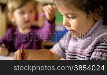 Little girls having fun at school, two happy female friends drawing with colors and crayons in kindergarten. Sequence