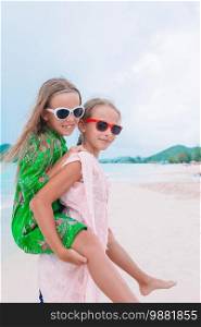 Little girls having fun at tropical beach playing together at shallow water. Adorable little sisters at beach during summer vacation. Kids have a lot of fun at tropical beach playing together