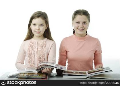 Little girls read books at the table isolated on white
