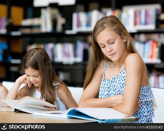 Little girls reading books in library. We love reading