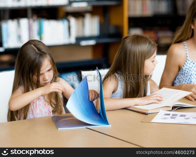 Little girls reading books in library. We love reading