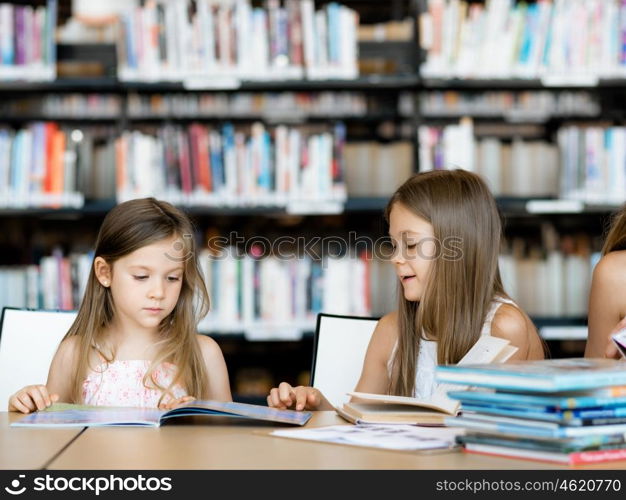 Little girls reading books in library. We love reading