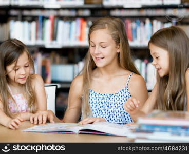 Little girls reading books in library. We love reading