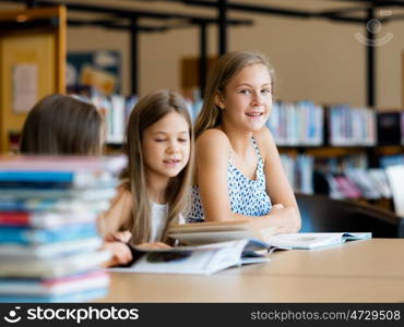 Little girls reading books in library. We love reading