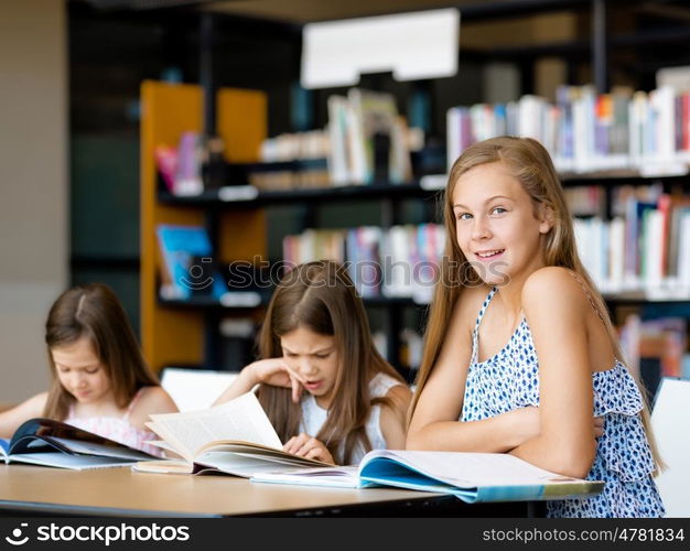 Little girls reading books in library. We love reading