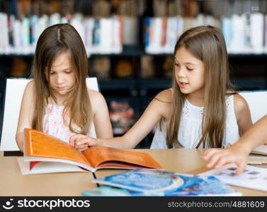 Little girls reading books in library. We love reading