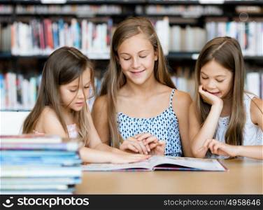 Little girls reading books in library. We love reading
