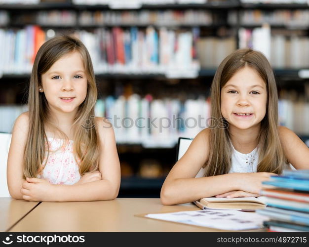 Little girls reading books in library. We love reading