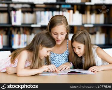 Little girls reading books in library. We love reading