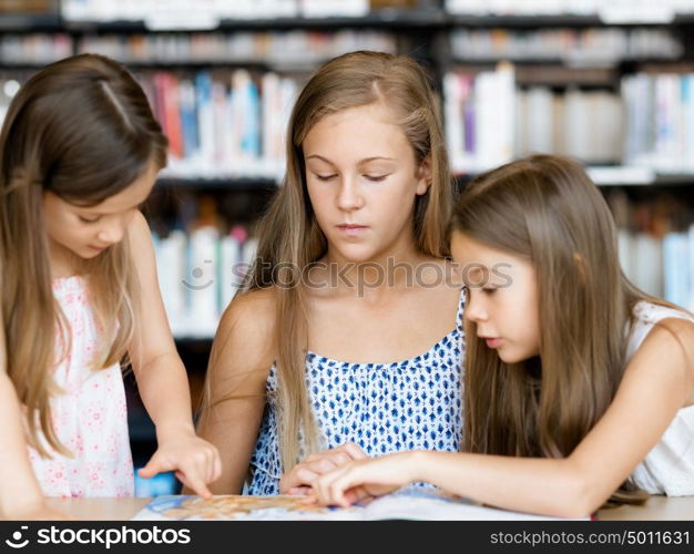 Little girls reading books in library. We love reading