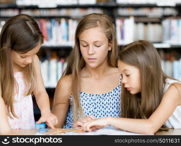 Little girls reading books in library. We love reading