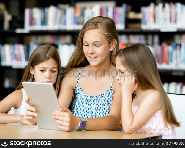 Little girls with a laptop in library. Technology and fun in the library