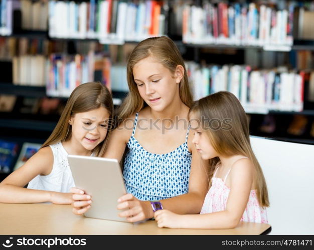 Little girls with a laptop in library. Technology and fun in the library