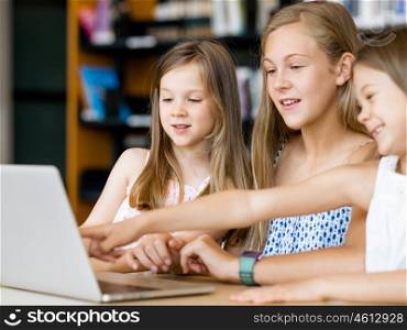 Little girls with a laptop in library. Technology in the library