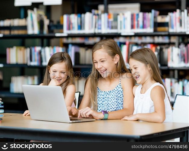 Little girls with a laptop in library. Technology in the library