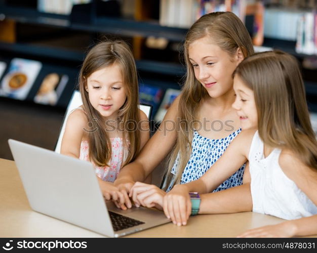 Little girls with a laptop in library. Technology in the library