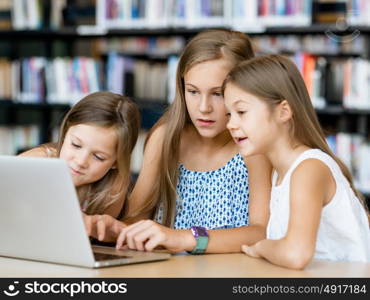 Little girls with a laptop in library. Technology in the library