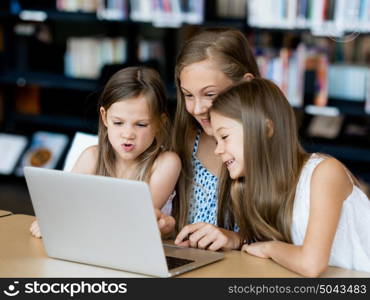 Little girls with a laptop in library. Technology in the library