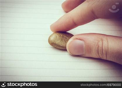 Little gold color pebble in the hand