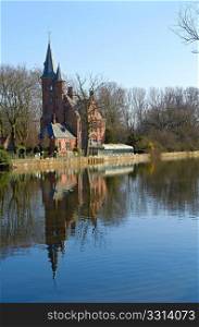 Little gothic palace on edge of Bruges Love lake. Clear spring day. Belgeum