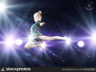 Little gymnast. Cute girl gymnast in performance costume jumping high