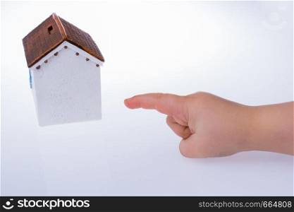 Little hand pointing at a model house on a white color background