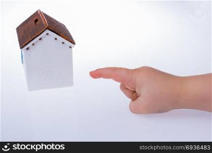 Little hand pointing at a model house on a white color background