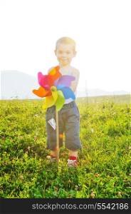 little happy child play with windmil toy and have ve fun while running on beautiful meadow at sunset