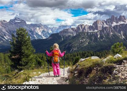 little happy girl hiker on a path at the mountains. Dolomites, Italy