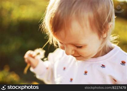 little happy girl in a field with a dandelion in hand