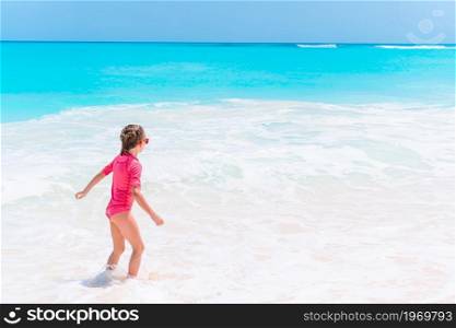 Little happy girl splashing in clear turquiose water in the sea. Cute little girl at beach during summer vacation
