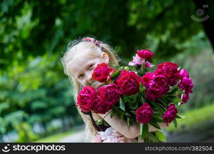 little happy girl with a bouquet of peonies