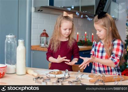 Little happy girls baking gingerbread cookies for Christmas at home kitchen - Image. Adorable happy little girls baking Christmas gingerbread cookies in Xmas eve
