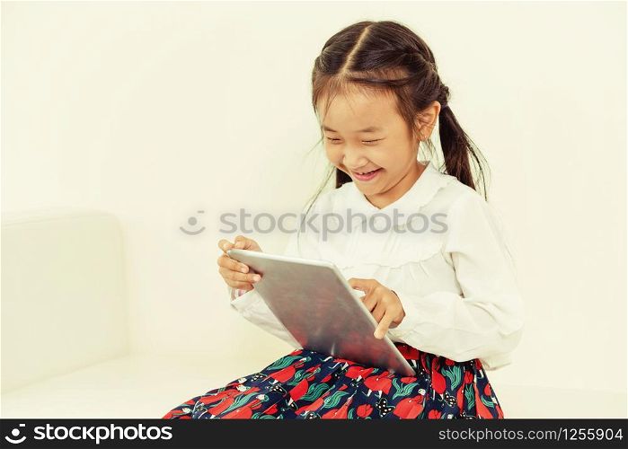 Little happy kid on white background with tablet computer. Childhood lifestyle.
