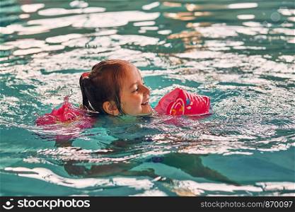 Little happy smiling girl playing in water in pool. Candid people, real moments, authentic situations