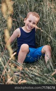 Little happy smiling kids playing in a tall grass in the countryside. Candid people, real moments, authentic situations