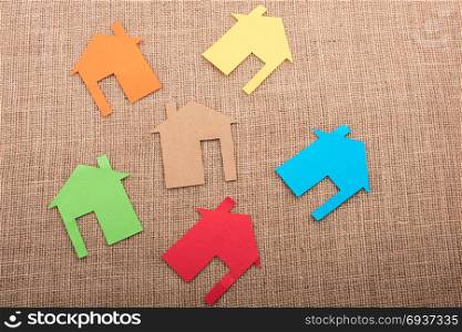 Little house shape cut out of colorful paper on a canvas background