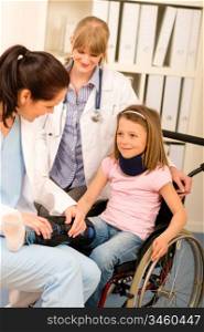 Little injured girl on wheelchair with doctors at medical office