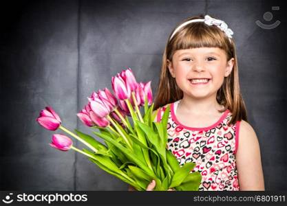 little irl with tulips in hands over dark wooden background