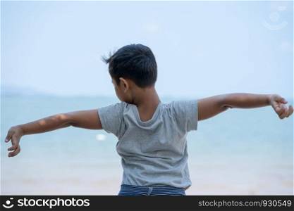 little kid boy stand on beach and stretch oneself