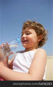 Little kid drinking bottle of water at the beach