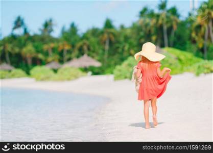 Little kid in hat on the beach during summer vacation. Adorable little girl in hat at beach during summer vacation