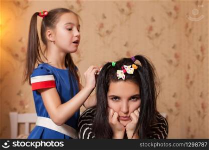 Little kid making hairstyle to her young mother.
