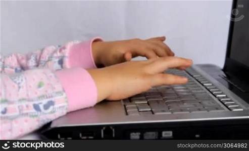 Little kid typimg on laptop keyboard
