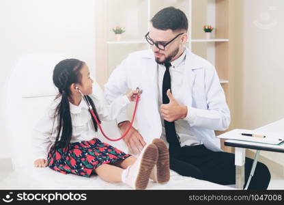 Little kid visit doctor in hospital office. The kid is happy and not afraid of the doctor. Medical and children healthcare concept.