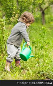 Little kid with watering can in the garden