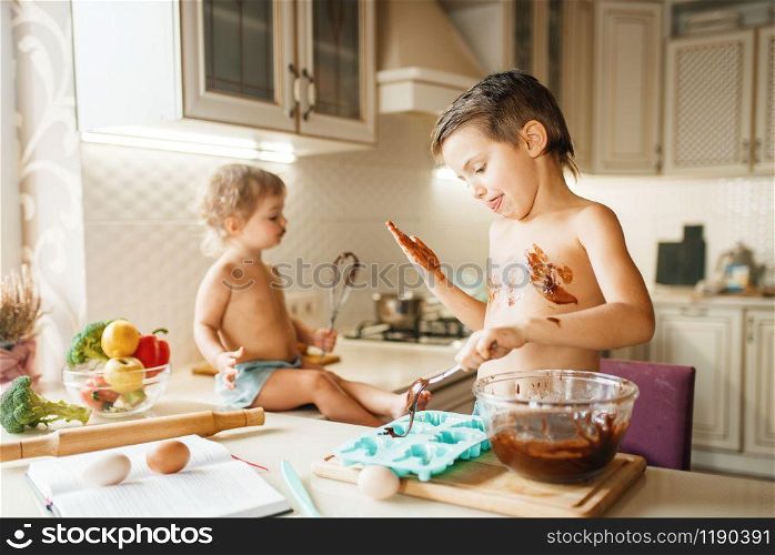 Little kids prepares pastry with melted chocolate. Cute boy and girl cooking on the kitchen. Happy children makes sweet dessert at the table