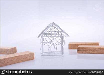 Little metal house and domino pieces on a light brown color background