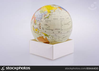 Little model globe put on a white box on a white background